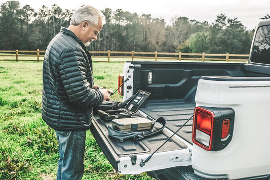 Man working in the truck bed on a grassy field.
